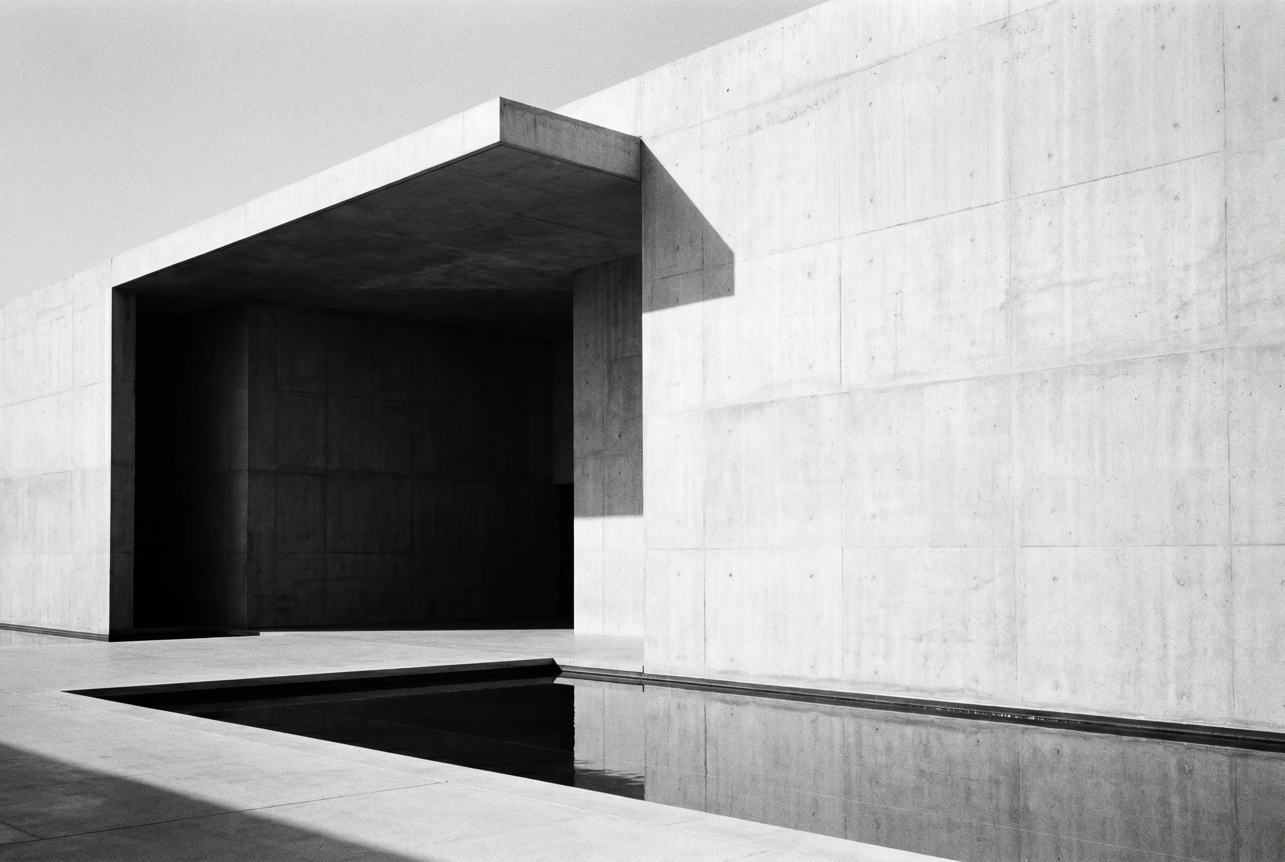 A contemporary museum-grade concrete facade in Abu Dhabi, light falling across a hard edge above a still reflecting pool